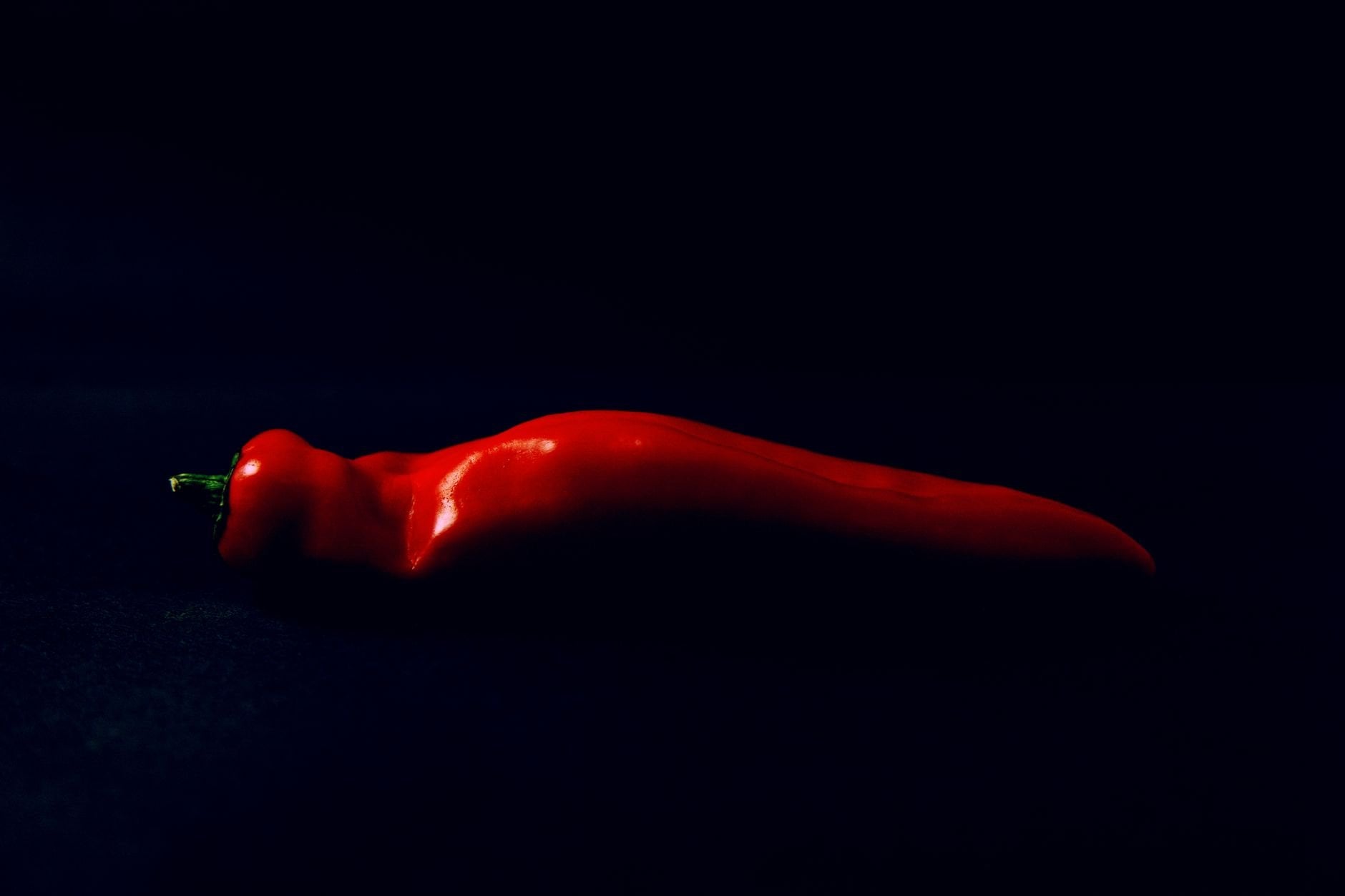 Vibrant red chili pepper against a deep dark background